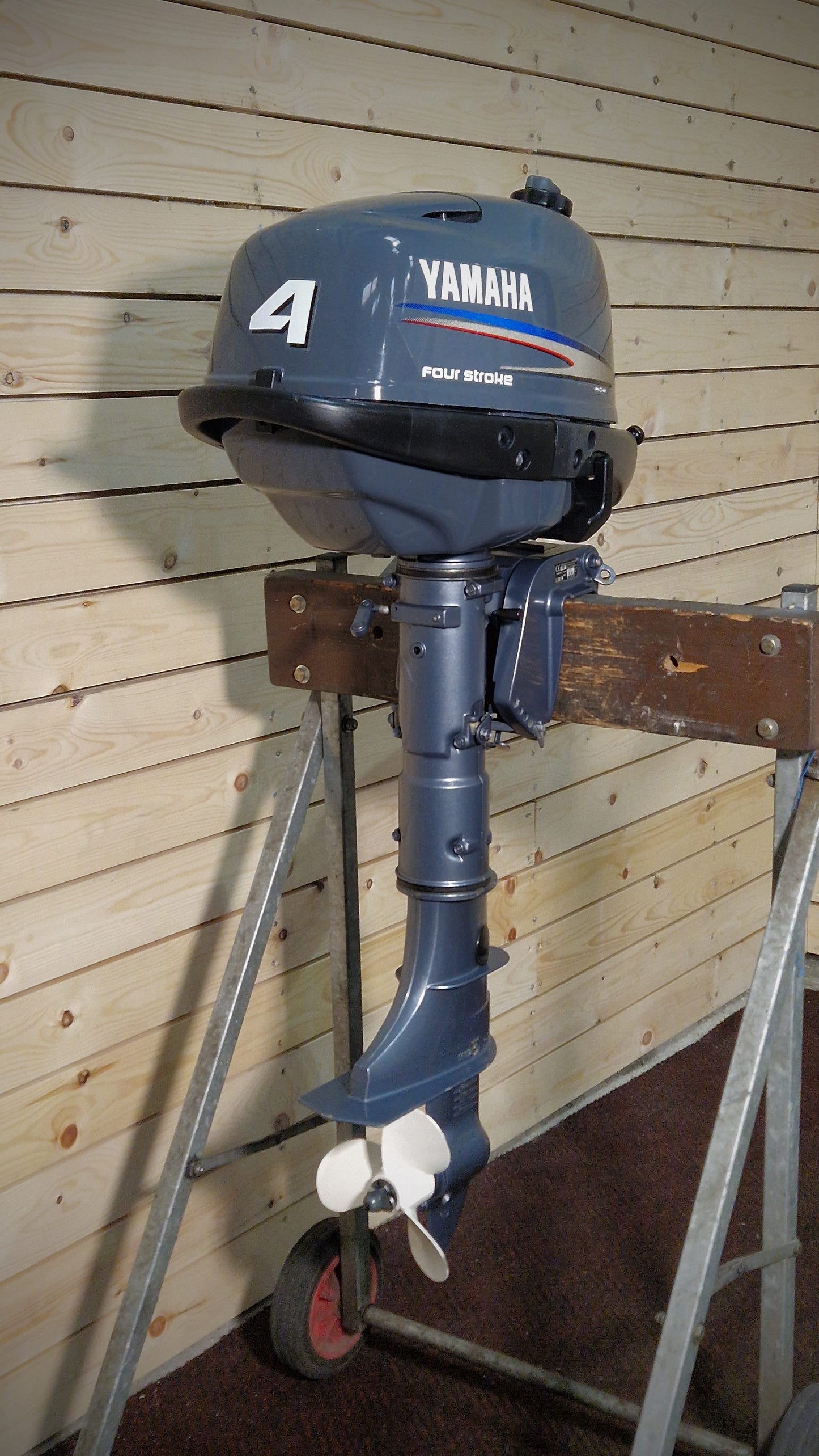 Yamaha outboard motor on a stand against a wooden wall