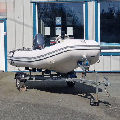 Inflatable boat on a trailer in front of a building with large windows.
