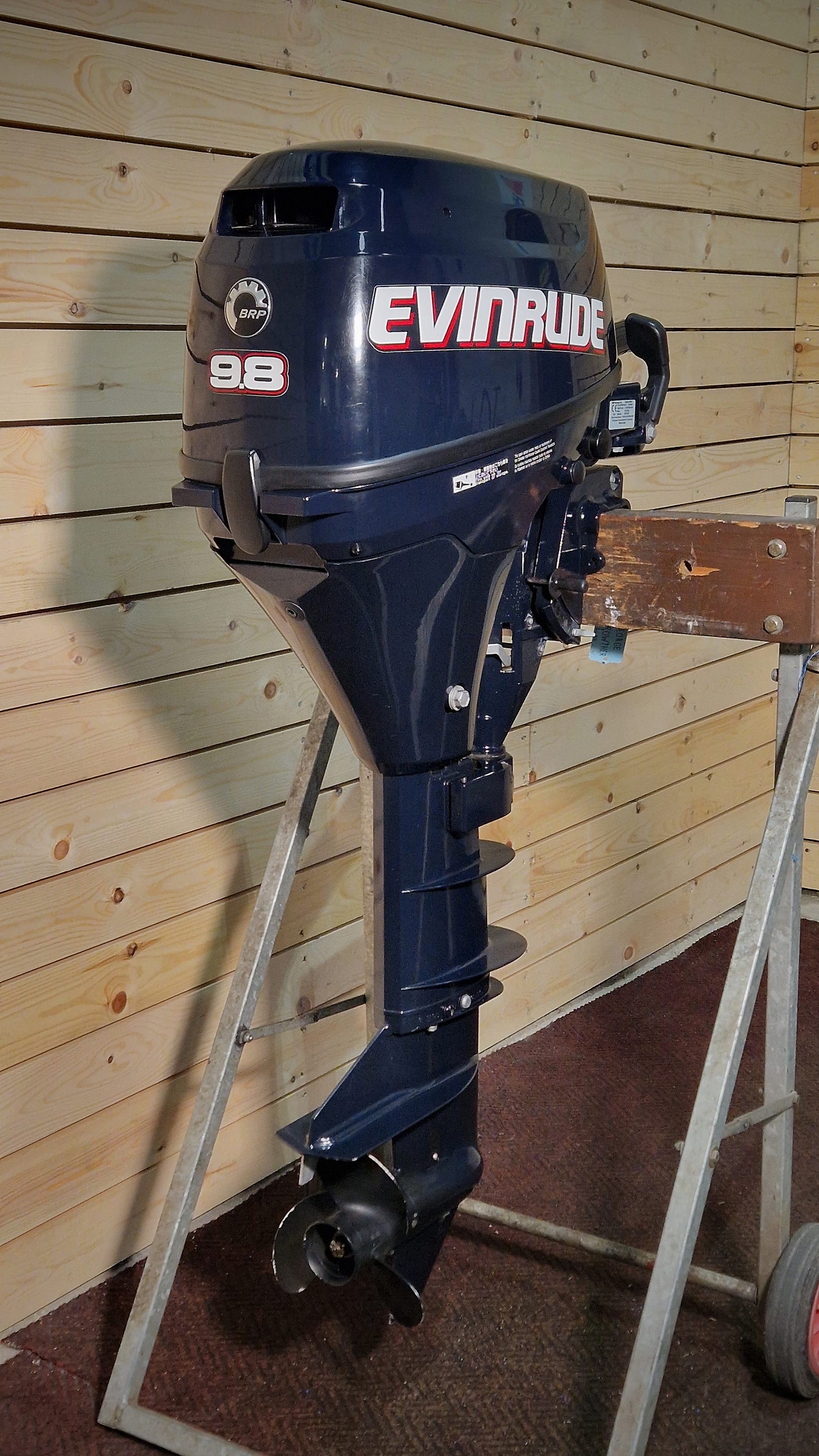 Evinrude outboard motor on a stand against a wooden wall