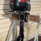 Suzuki outboard motor on a stand against a wooden wall