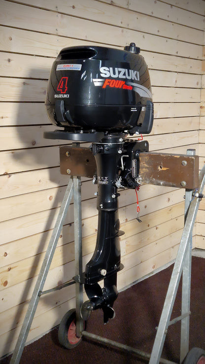 Suzuki outboard motor on a stand against a wooden wall